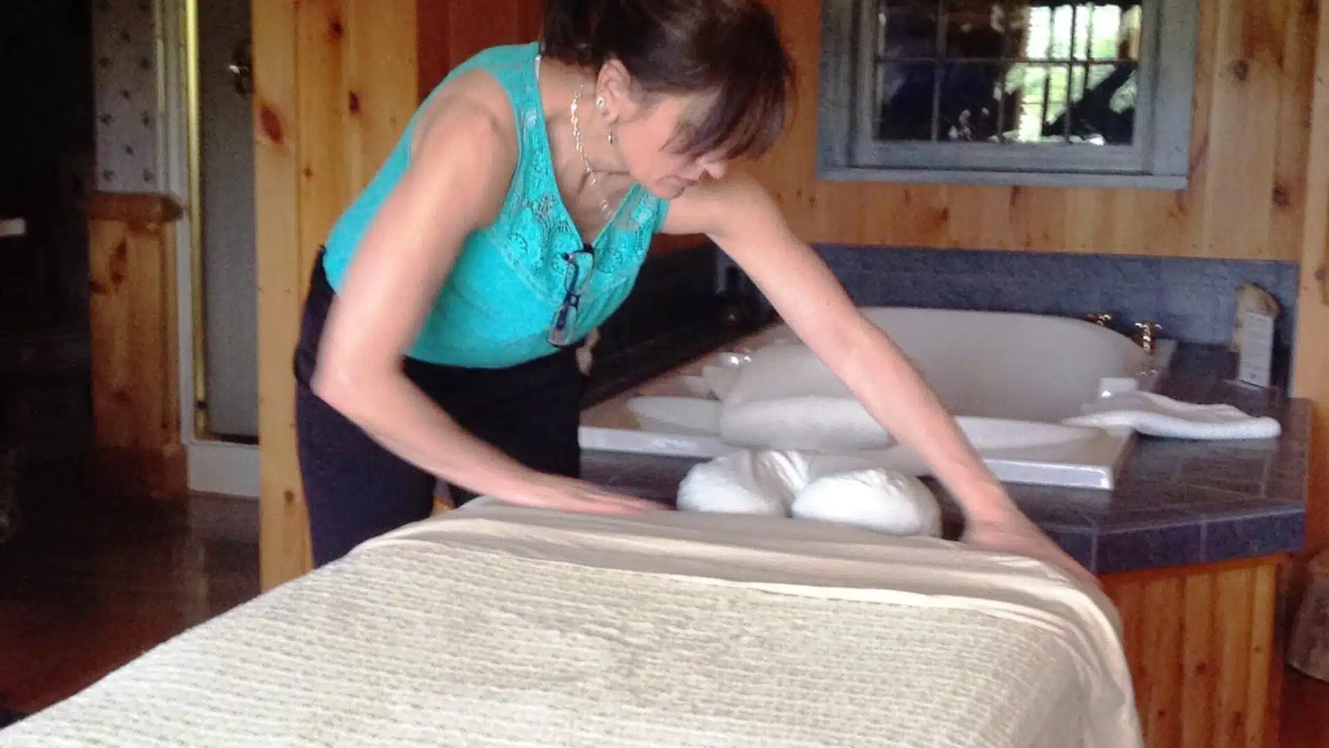 Massage therapist making up spa bed in Cedar Glen Guestroom|woman getting a massage