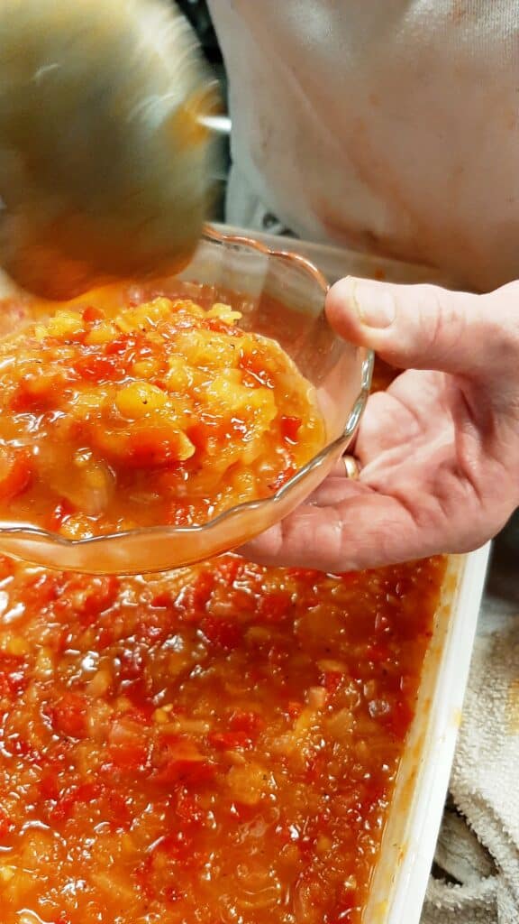 chef spooning pepper relish into a glass bowl