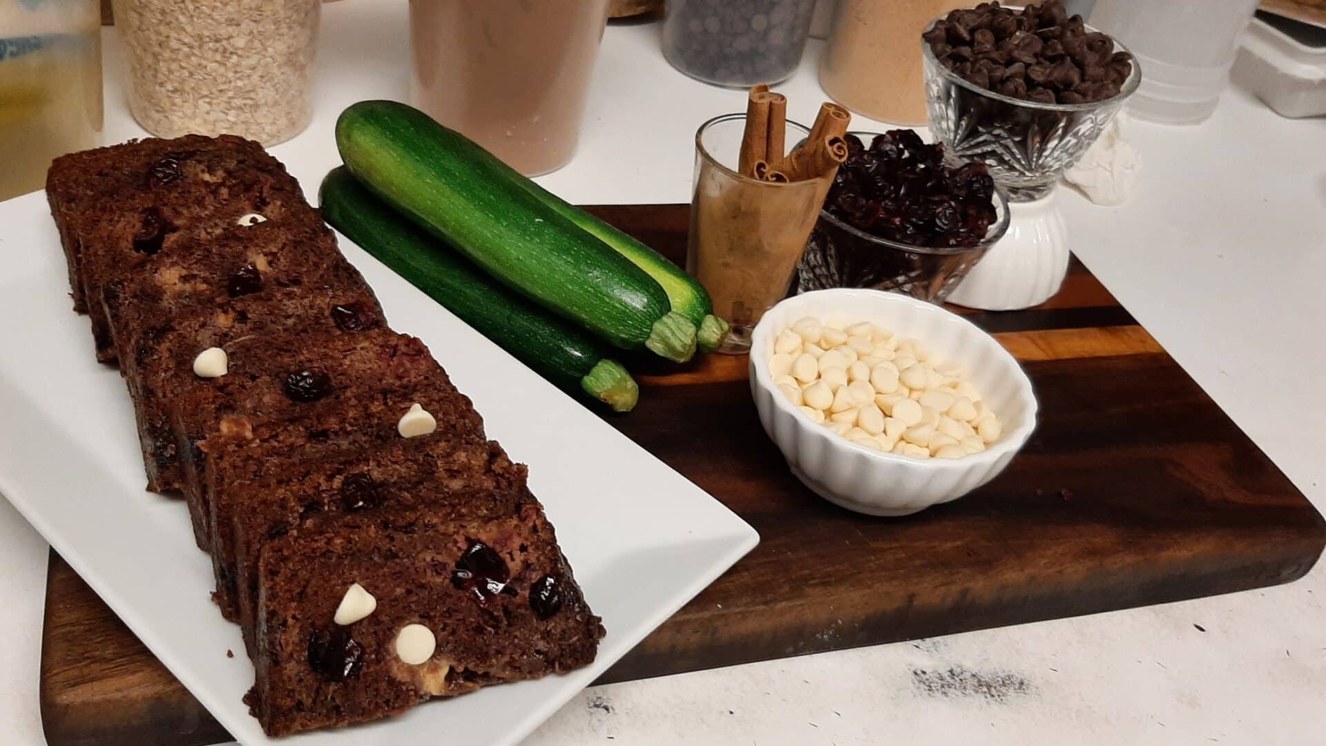 sliced chocolate zucchini cake next to bowls of ingredients