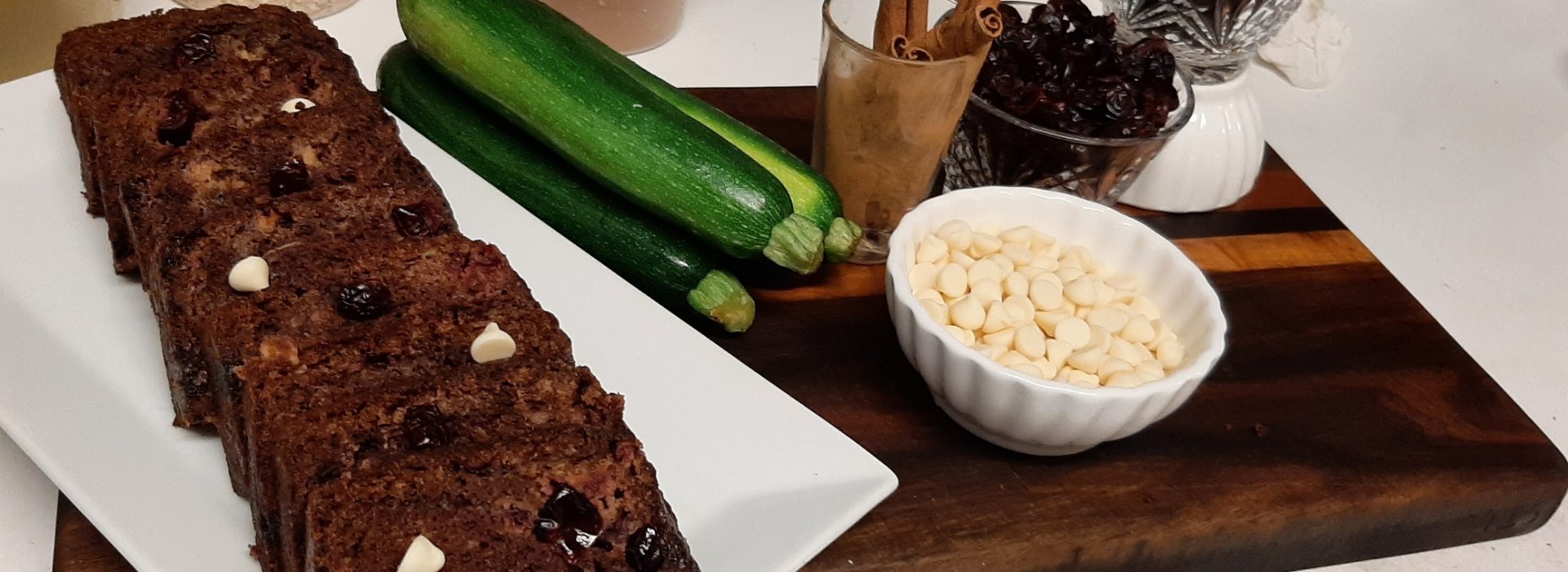 sliced chocolate zucchini cake next to bowls of ingredients