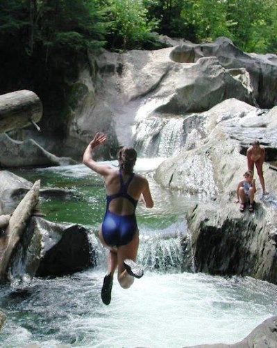 girl jumping in the water at a Swimming hole in Vermont