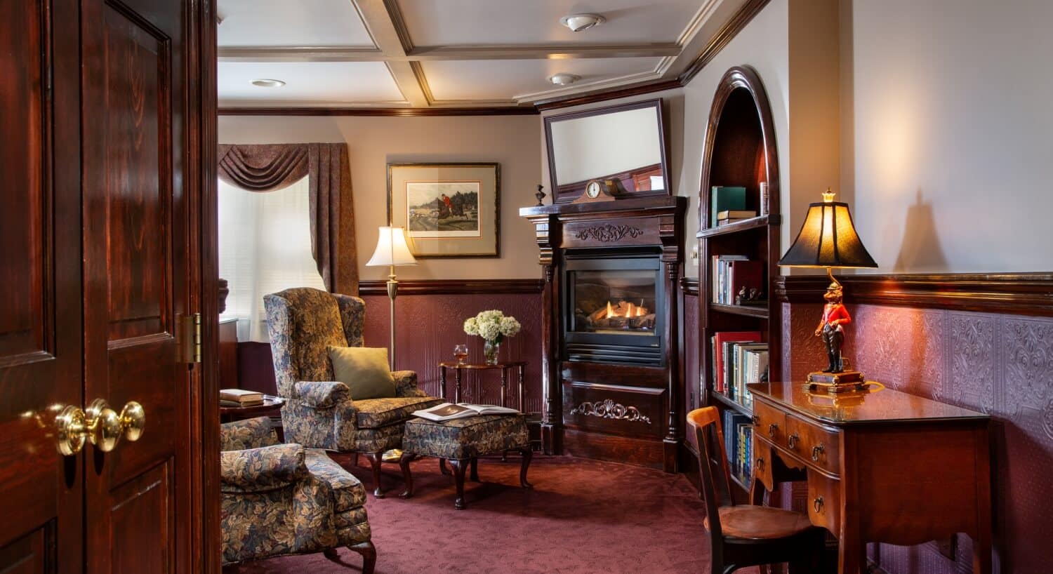 glowing fireplace next to arched bookshelf