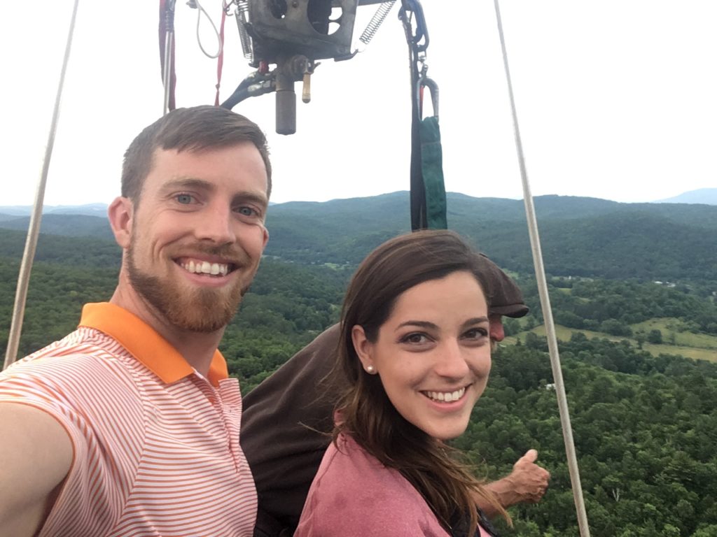 young smiling couple with balloonist high above Vermont in a balloon