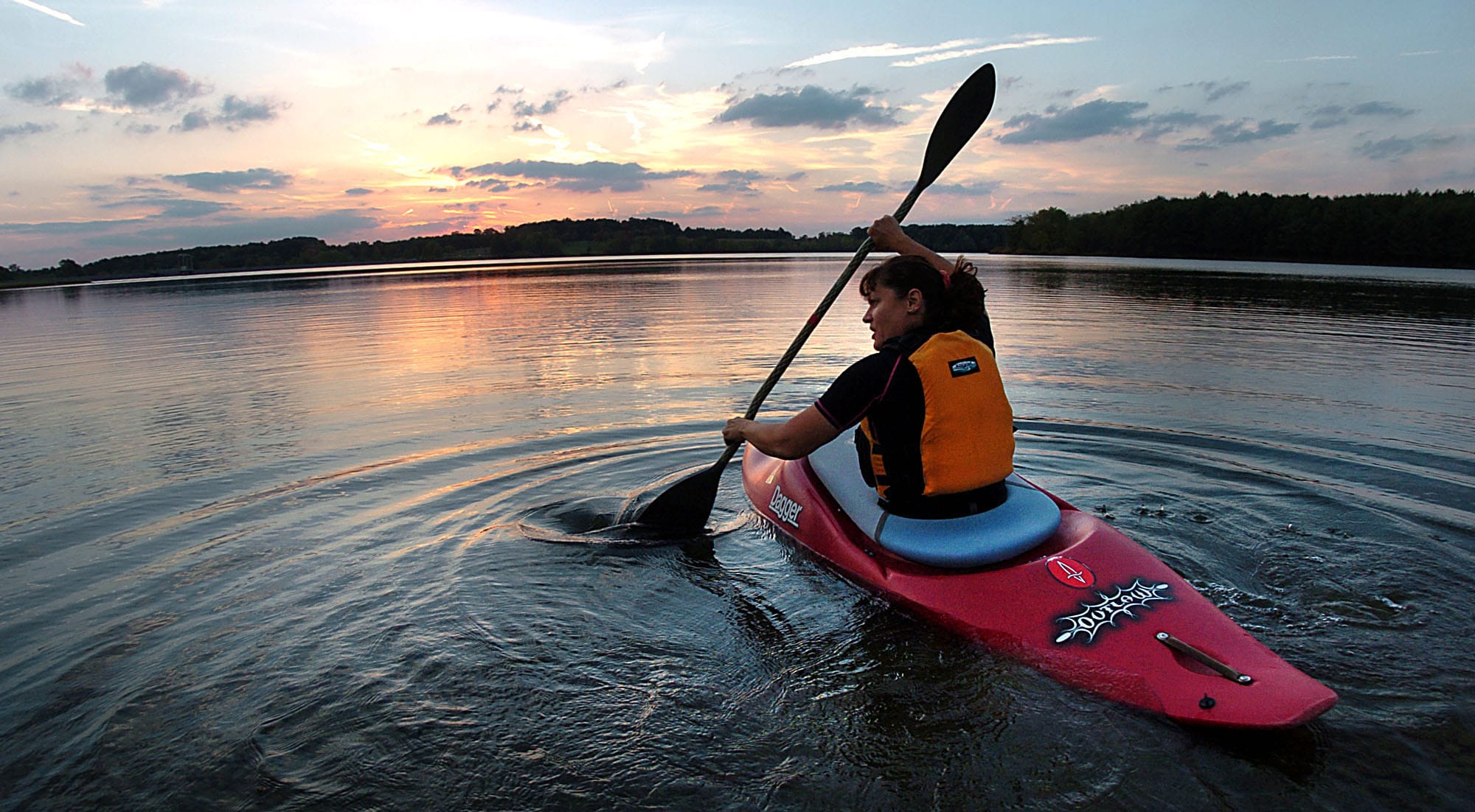 girl paddling a kayak on the river at sunset|woman having a great time paddling in a kayak on the Clyde River