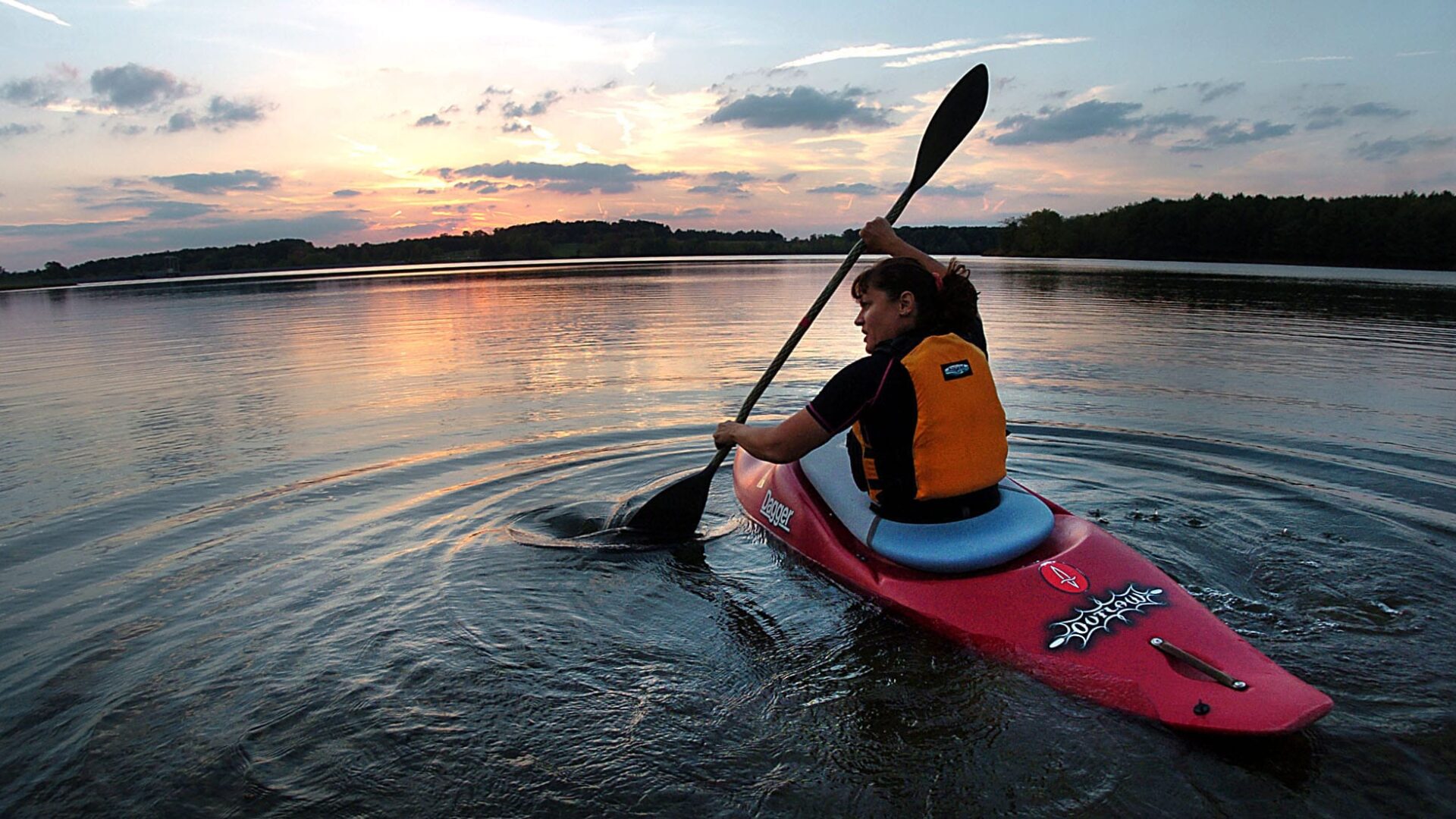 girl paddling a kayak on the river at sunset|Best places to kayaking in Vermont