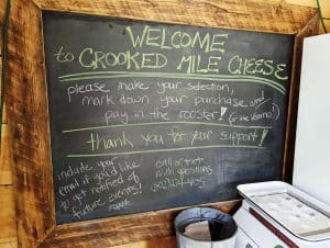 Blackboard sign at Crooked Mile Cheese Farm telling folks how to pay.