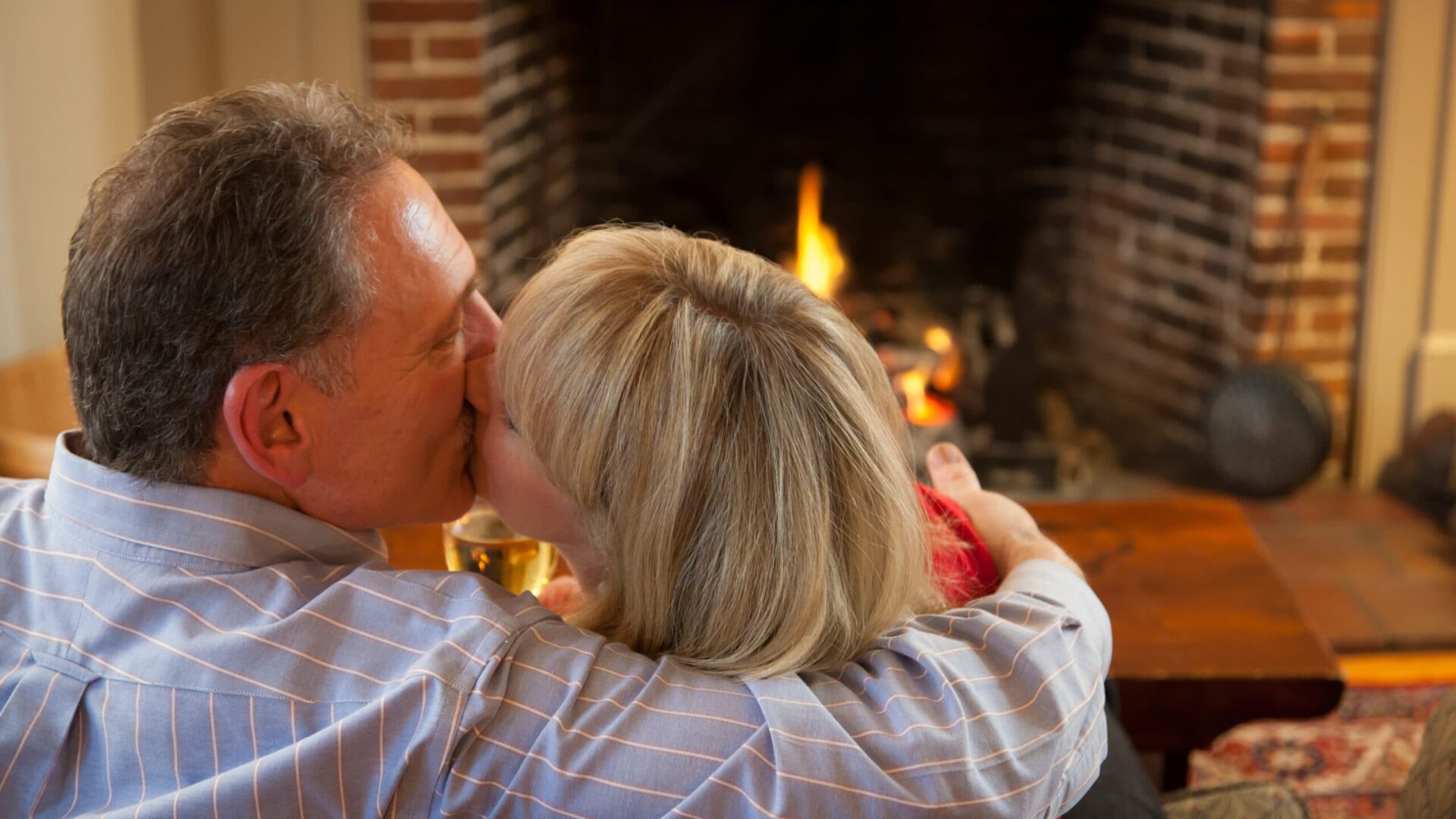couple kissing in front of a fireplace