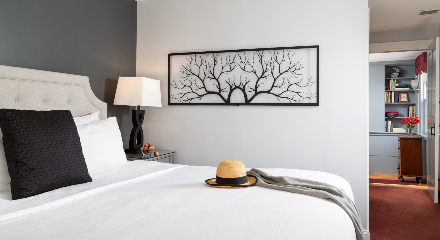 hat on a king bed with metal tree art on gray wall