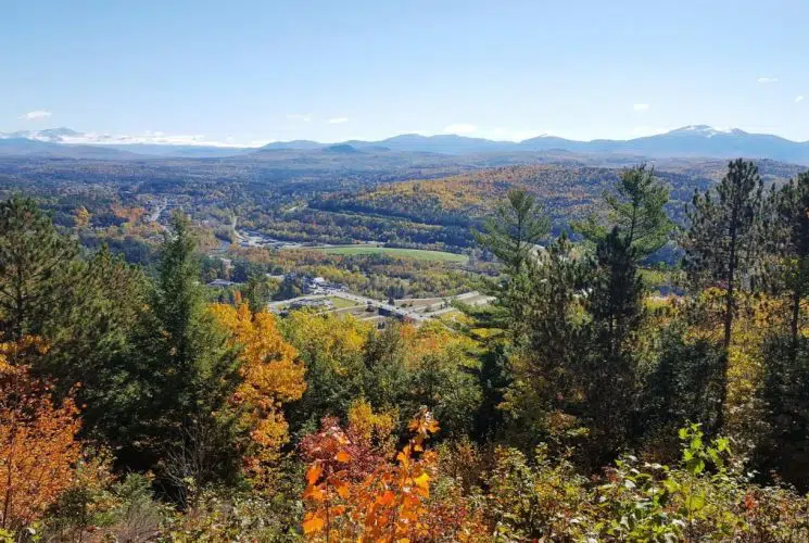 View of a small town from a nearby mountain side full of green, yellow, and red trees