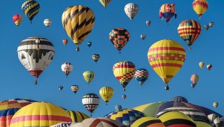 several colorful hot air balloons rising up to a blue sky