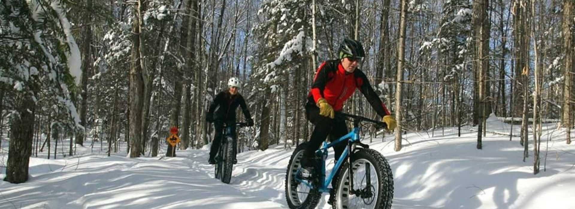 Kingdom Trails fat biking & cross country ski trails|two fat bikers and a cross country skier at kingdom trails|3 winter fat bikiers at Kingdom Trails Fat Biking & Cross Country Ski center
