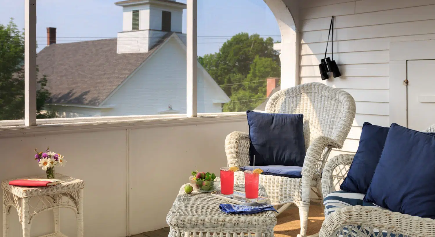 White wicker patio furniture with navy pillow accents on an open patio balcony