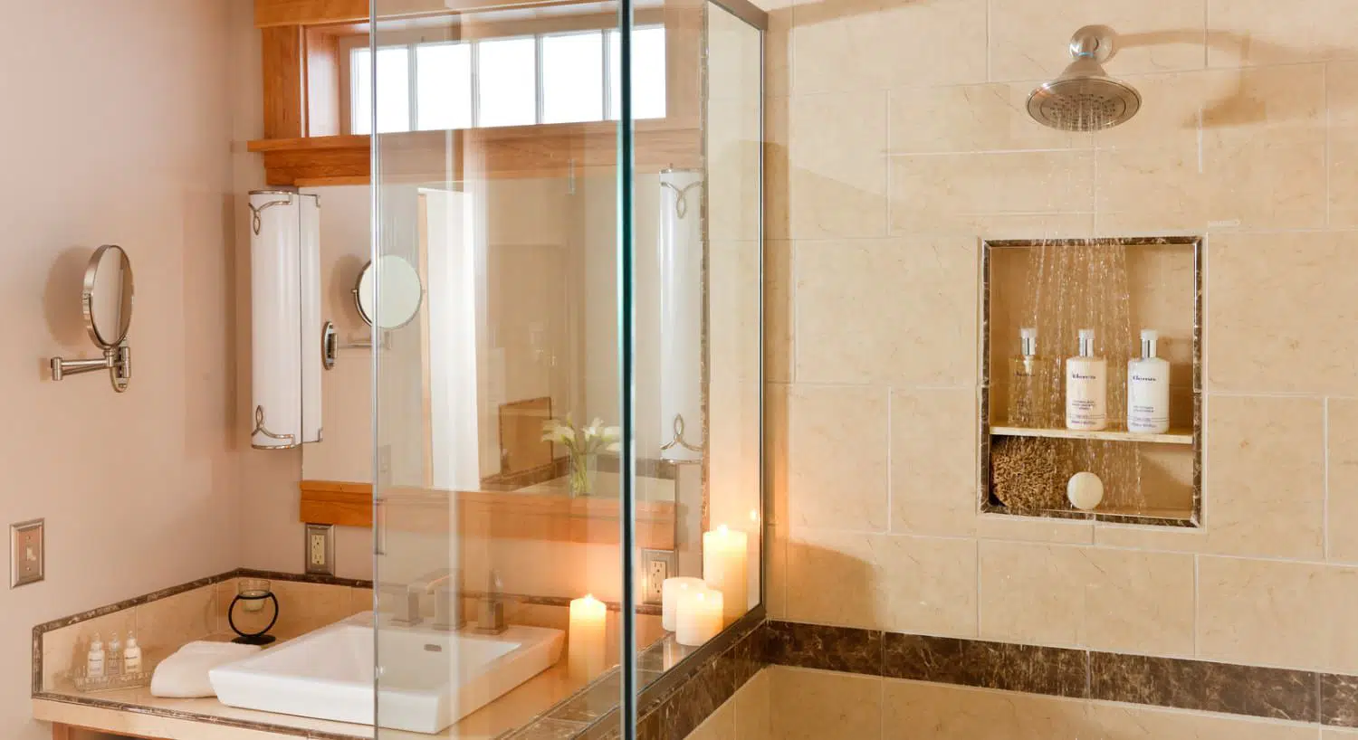 Bathroom with glass enclosed light-colored tiled shower and white sink