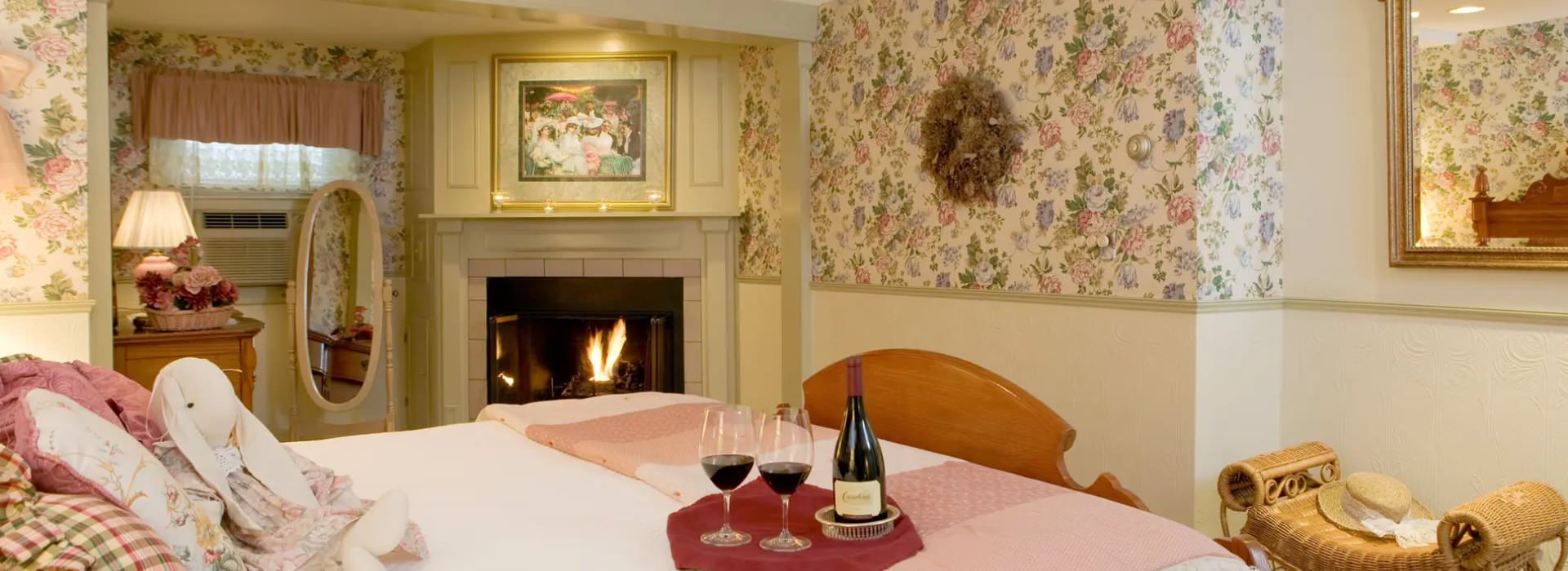 Bedroom with floral wallpaper, light-colored wall below chair rail, wooden bed with white bedding, and fireplace