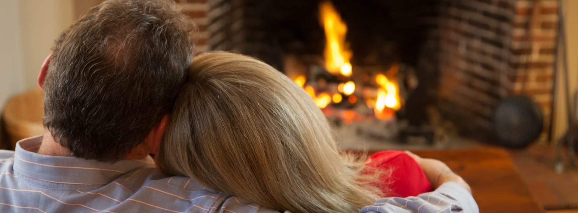 snuggling couple in front of a fireplace|blue-green water in a tub for two with views of a fireplaced sitting area.