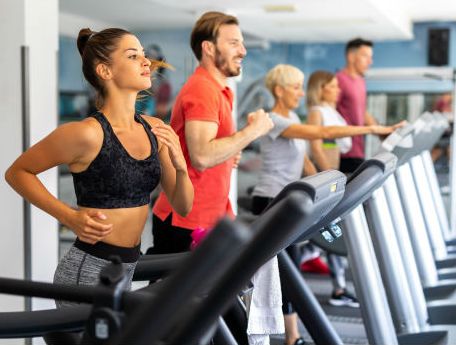 five people on a row of treadmills at the gym