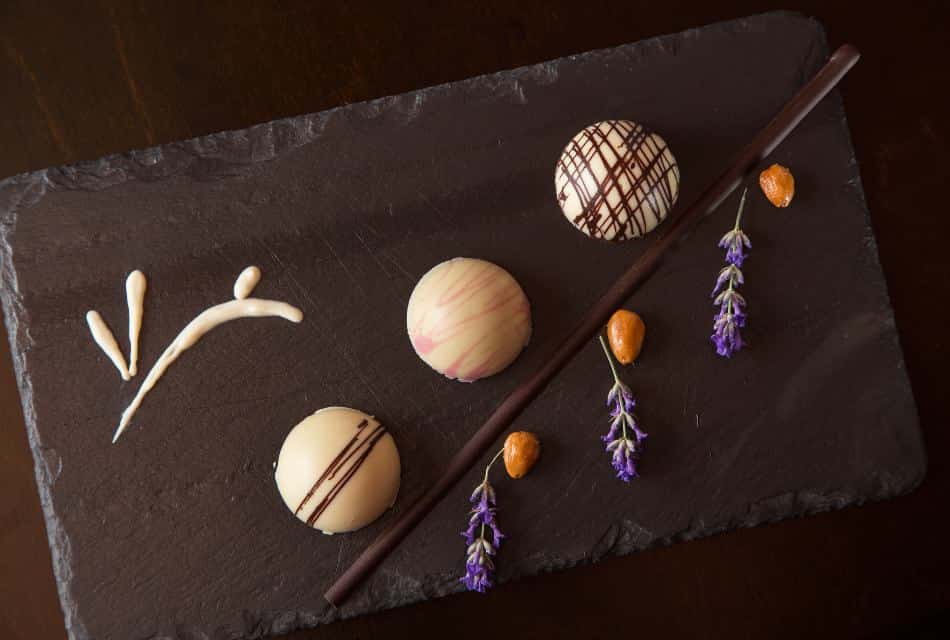 Dark gray slate tile with decorated white chocolate round truffles with Rabbit Hill logo bunny drawn in white chocolate