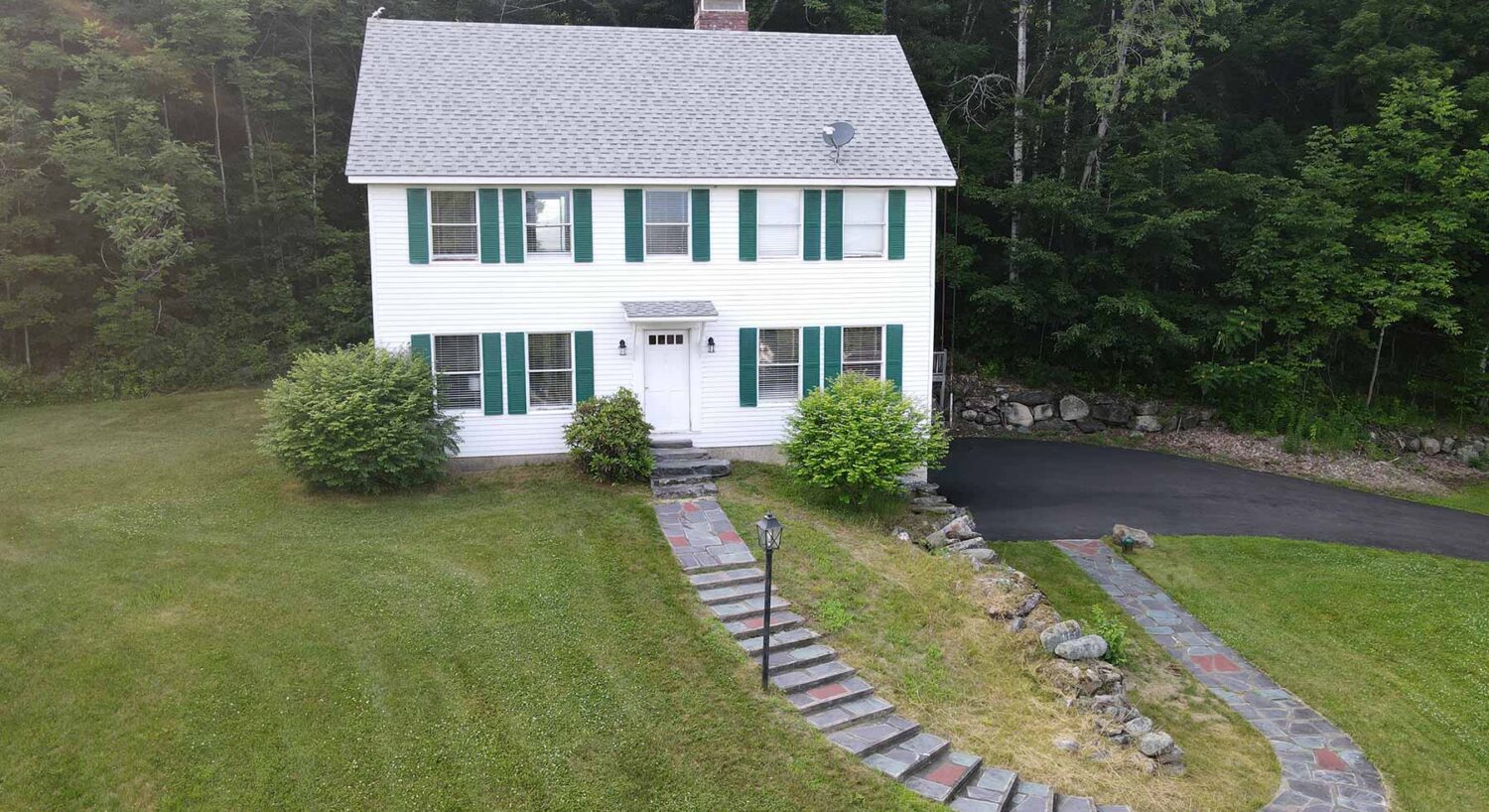 Classic white two-story house with green shutters and stone walkway at one of the inviting hotels near St Johnsbury VT